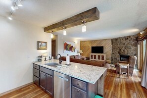 A kitchen with a granite countertop, stainless steel appliances, and a stone wall. - Intimate condo with fireplace, washer/dryer, outdoor pool & hot tub (Steamboat Springs)