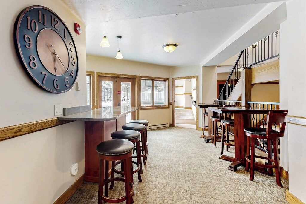 Eine Bar mit Hockern, einer großen Wanduhr und einer Treppe.