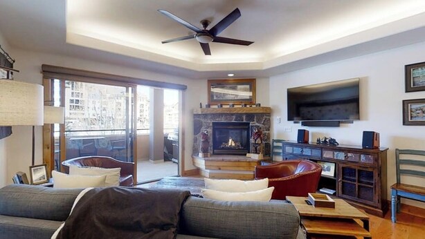 Ein Wohnzimmer mit Sofa, Sesseln, Kamin, Fernseher und Deckenventilator.