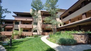 Un immeuble à plusieurs étages doté de balcons, d’un jardin aménagé et d’un sentier.