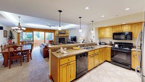 A modern kitchen with wooden cabinets, a central island, a dishwasher, a stove, and a microwave. - Canyon Creek A103 - Modern, spacious condo w/ a shared pool, hot tub, & gym - close to the slopes (Steamboat Springs)