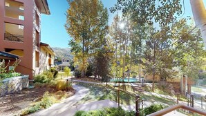 A courtyard with a pathway, trees, and a building with balconies. - Canyon Creek A103 - Modern, spacious condo w/ a shared pool, hot tub, & gym - close to the slopes (Steamboat Springs)