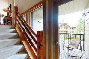 A wooden staircase leading to a balcony with a view of a house and a chair. - Large split-level condo with valley & mountain views plus hot tubs (Steamboat Springs)