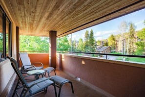 Ein Balkon mit Holzboden, zwei Stühlen und Blick auf eine Wohngegend.