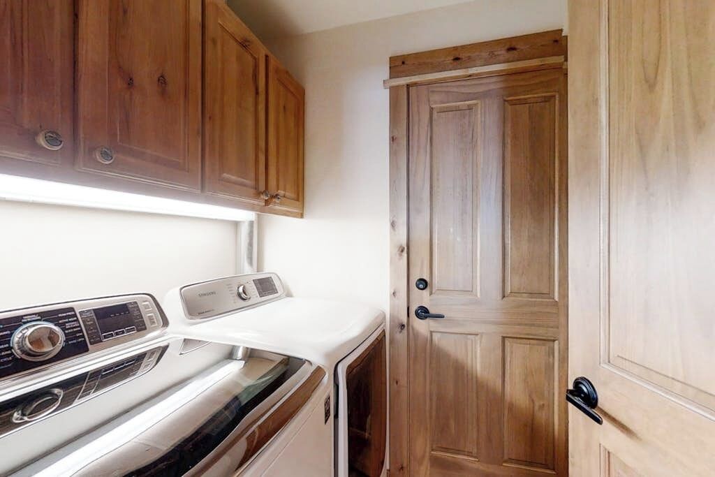 A compact kitchen with wooden cabinets, a white countertop, and a door.