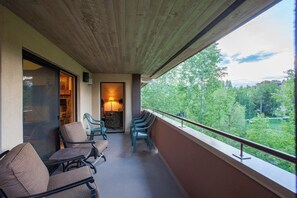 A balcony with seating, a lamp, and a view of greenery. - Top-floor condo w/ great deck & shared pool - short walk to lifts & restaurants (Steamboat Springs)