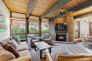 A cozy living room with a fireplace, comfortable seating, and large windows. - The Lodge at Steamboat A106 Lovely condo near lift with hot tubs, pool & free shuttle (Steamboat Springs)
