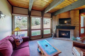 Ein Wohnzimmer mit Kamin, großen Fenstern und einer Couch.