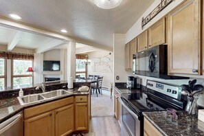 Eine moderne Küche mit Granit-Arbeitsplatten, Edelstahlgeräten und Holzschränken, sowie einem Essbereich mit Tisch und Stühlen.