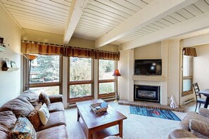 Ein Wohnzimmer mit Kamin, Fernseher und einem großen Fenster.