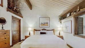 A bedroom with a wooden bed, two bedside tables with lamps, a wooden dresser, a mirror, and a framed picture on the wall. - Top-level condo close to summer fun with grills, hot tubs & parking (Steamboat Springs)