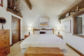 A bedroom with a wooden bed, two bedside tables with lamps, a wooden dresser, a mirror, and a framed picture on the wall. - Top-level condo close to summer fun with grills, hot tubs & parking (Steamboat Springs)