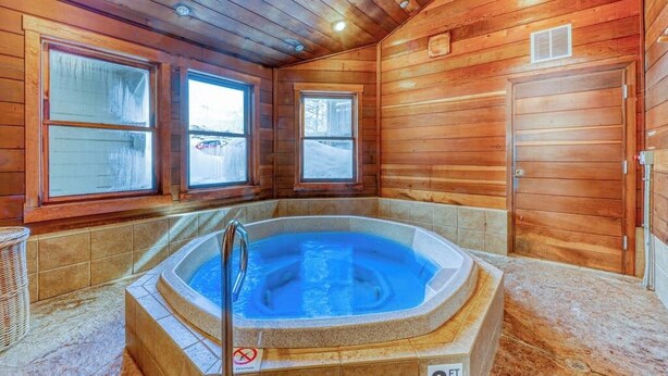 Eine Holzhütte mit Whirlpool, großen Fenstern und einer Tür.