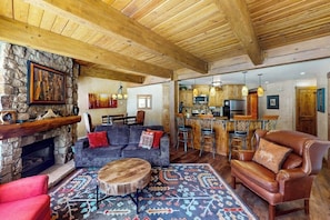 Ein rustikales Interieur mit Kamin aus Stein, einer Couch, einem Ledersessel und einer Bar.