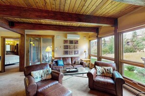 Ein großzügiges Wohnzimmer mit Ledersofas, einem Glastisch und großen Fenstern mit Blick ins Freie.