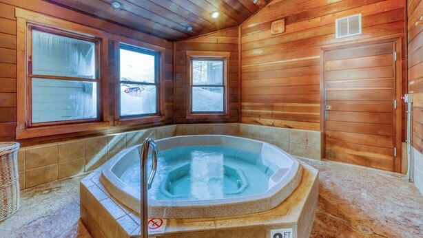 Eine Holzhütte mit Whirlpool, großen Fenstern und einer Tür.