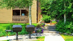 Ein Gebäude mit einem Holzbalkon, Solarkochgrills und einem gepflegten Garten mit Stufen zum Eingang.