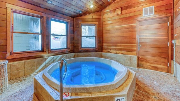 Eine Holzhütte mit Whirlpool, großen Fenstern und einer Tür.