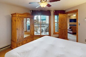 A bedroom with a bed, a wooden wardrobe, a ceiling fan, and a sliding glass door leading to an outdoor patio. - Steamboat home near gondola with pool, hot tub & washer/dryer (Steamboat Springs)