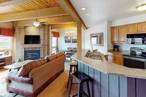 A kitchen with a bar area, a fireplace, and a dining area with a sofa. - Steamboat home near gondola with pool, hot tub & washer/dryer (Steamboat Springs)
