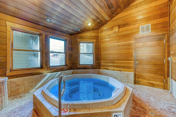 A wooden cabin interior with a hot tub, large windows, and a door. - Steamboat home near gondola with pool, hot tub & washer/dryer (Steamboat Springs)