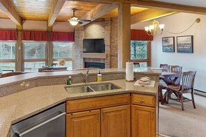 A kitchen with granite countertops, wooden cabinets, a built-in oven, and a dining area with a table and chairs. - Steamboat home near gondola with pool, hot tub & washer/dryer (Steamboat Springs)