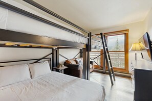 Ein Schlafraum mit Etagenbetten, einem Schreibtisch, einem Stuhl, einer Lampe und Blick ins Freie.