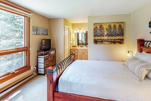 A bedroom with a bed, dresser, TV, and a painting on the wall.