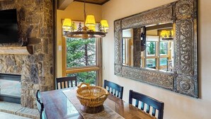 Un comedor con pared de piedra, un espejo grande y una araña.