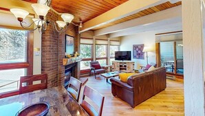 Ein geräumiges Wohnzimmer mit Kamin, Holzboden und großen Fenstern.