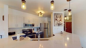 Una cocina moderna con armarios blancos, electrodomésticos de acero inoxidable e isla de mármol.