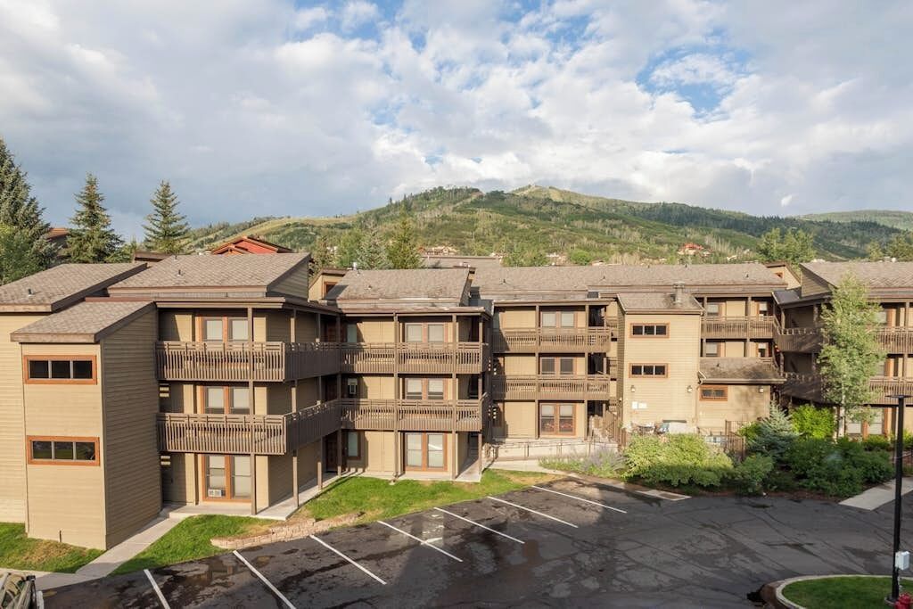 A multi-story hotel with balconies and a parking lot.