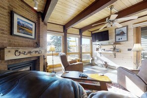 Ein gemütliches Wohnzimmer mit Kamin, Ledersofa und Deckenventilator.