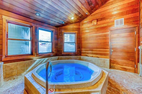 Eine Holzhütte mit Whirlpool, großen Fenstern und einer Tür.