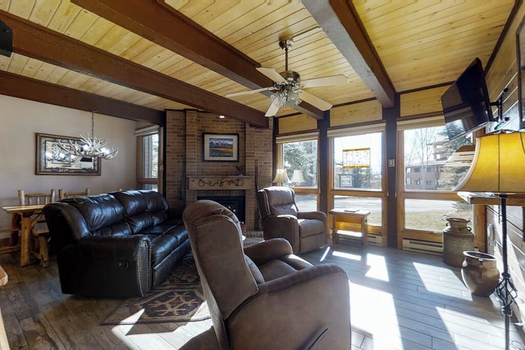 A cozy living room with a fireplace, leather sofas, and a ceiling fan.