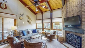 A living room with a fireplace, leather furniture, mounted animal heads, and a television. - Steamboat Springs condo with pool, hot tub & balcony (Steamboat Springs)