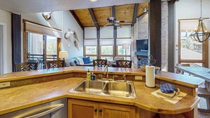 A kitchen with a wooden countertop, double sink, and a dining area with a bench and chairs. - Steamboat Springs condo with pool, hot tub & balcony (Steamboat Springs)