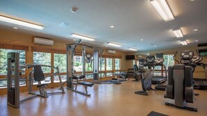 A gym with various exercise equipment, large windows, and a wooden interior. - Canyon Creek A105 - Family-friendly condo w/mountain views, balcony, shared hot tub & outdoor pool (Steamboat Springs)