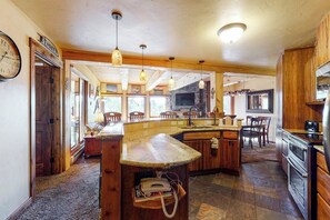 A kitchen with a stone countertop, wooden cabinets, and a built-in stove. - Convenient 1st-floor Steamboat chalet with pool, hot tubs & washer/dryer (Steamboat Springs)