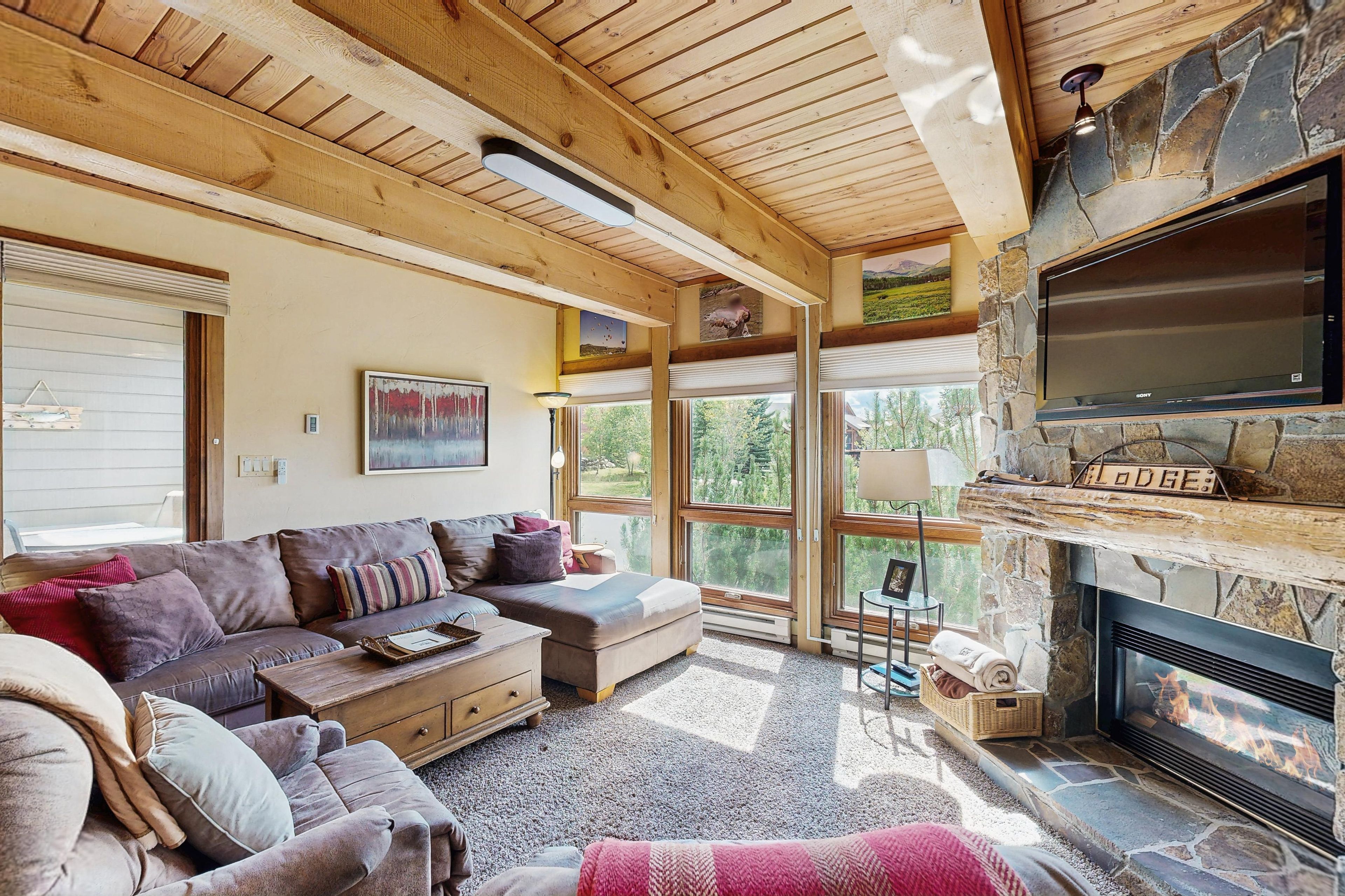 A cozy living room with a stone fireplace, a large window, and a comfortable sofa.