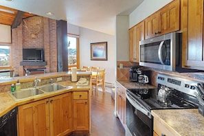 A kitchen with wooden cabinets, a built-in microwave, a stove, and a sink. - Spacious condo with pool, hot tub & washer/dryer - next to Steamboat ski lifts (Steamboat Springs)