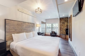 Ein Hotelzimmer mit einem großen Bett, einem Fernseher, einem Kamin aus Stein und einem Fenster.