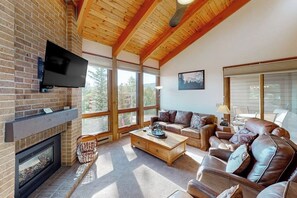 Ein Wohnzimmer mit Kamin, Ledersofas, einem Couchtisch und einem an einer Ziegelwand montierten Fernseher.