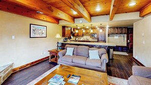 Ein Wohnzimmer mit Sofa, Couchtisch und einer Küche im Hintergrund.