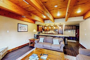 Ein Wohnzimmer mit Sofa, Couchtisch und einer Küche im Hintergrund.