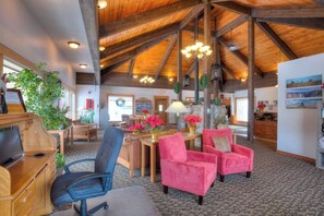 A spacious room with a high wooden ceiling, a wooden desk, two chairs, a television, and a large window. - Great condo w/ remodeled kitchen, balcony, & ski-in/ski-out access to mountain (Steamboat Springs)