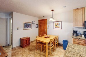 Una cocina compacta con una mesa de comedor, armarios de madera y un cubo de basura.