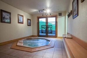 A room with a hot tub, a balcony with a view, and framed pictures on the walls. - Great condo w/ remodeled kitchen, balcony, & ski-in/ski-out access to mountain (Steamboat Springs)