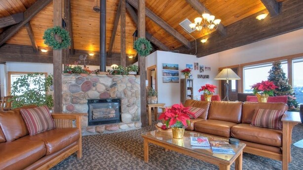 Ein gemütliches Wohnzimmer mit Kamin aus Stein, Ledersofas und Holzboden.