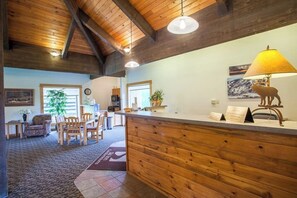 A reception area with a wooden reception desk, a lamp, a framed picture, and a plant. - Great condo w/ remodeled kitchen, balcony, & ski-in/ski-out access to mountain (Steamboat Springs)